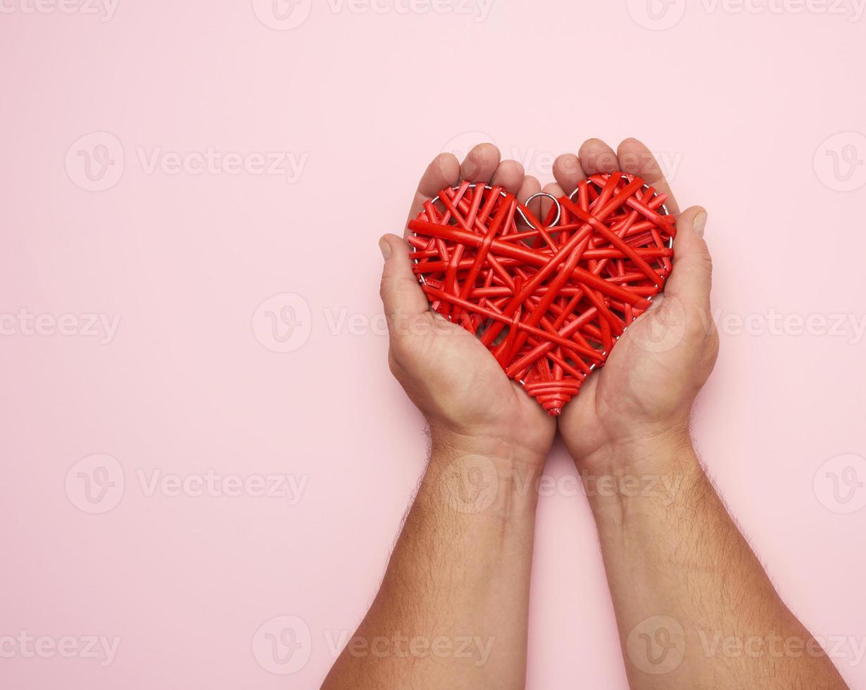 twee mannetje handen Holding een rood rieten hart Aan een roze achtergrond, foto