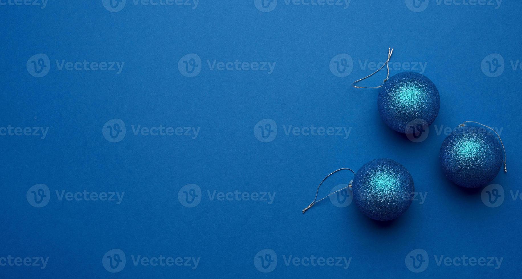 blauw glimmend Kerstmis ballen Aan een blauw achtergrond, feestelijk backdrop foto