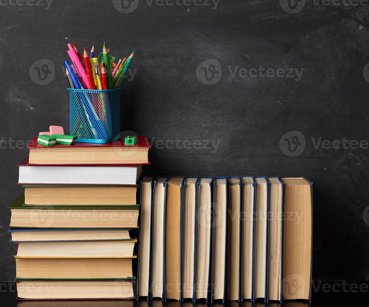 stack van divers boeken, schrijfbehoeften Aan zwart krijt bord achtergrond, terug naar school- foto