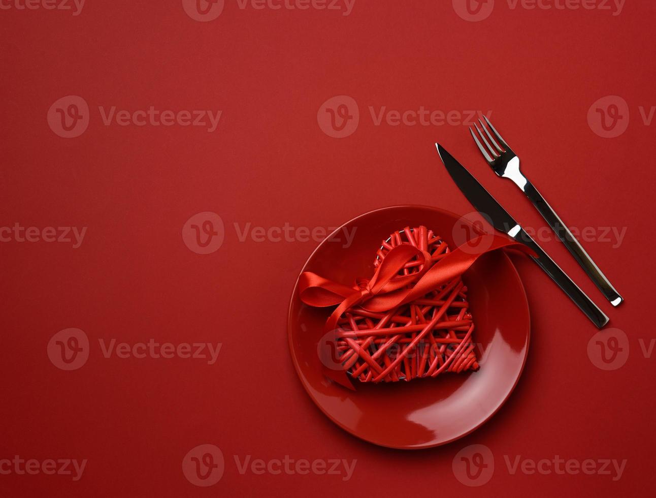 ronde keramisch bord en vork met mes Aan rood achtergrond, feestelijk tafel instelling foto