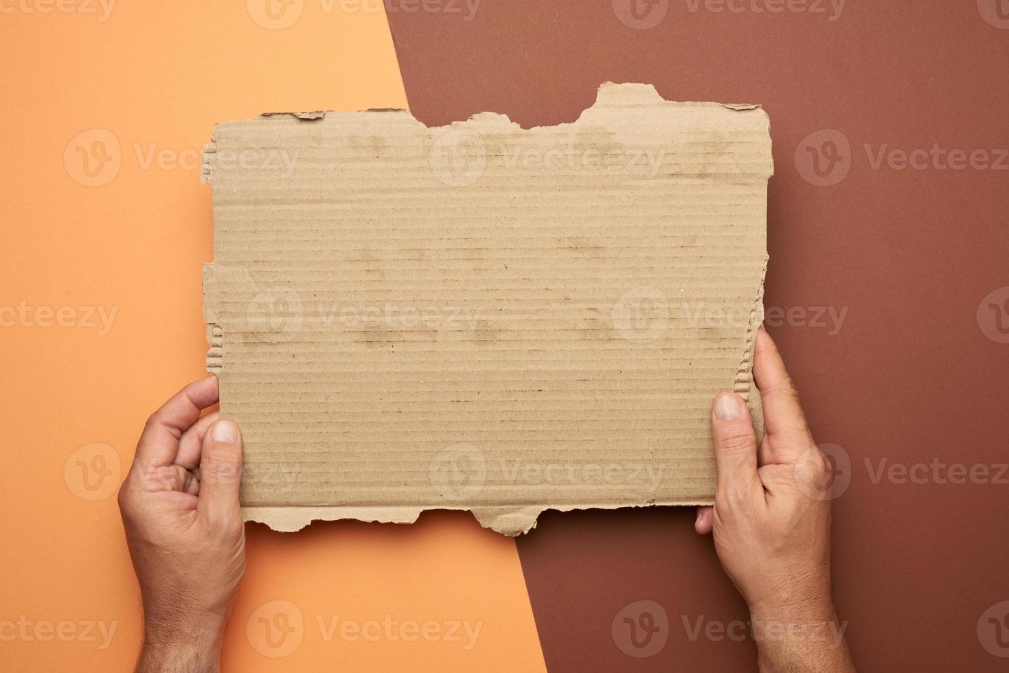 twee mannetje handen houden een blanco gescheurd stuk van bruin papier foto