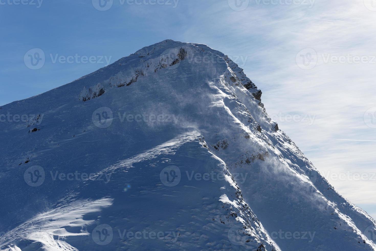 visie van berg top Aan een heel winderig zonnig dag. wind wervelende de sneeuw in de lucht. buitenshuis winter wandeltocht. winter reizend. avontuur en verkennen de bergen. foto