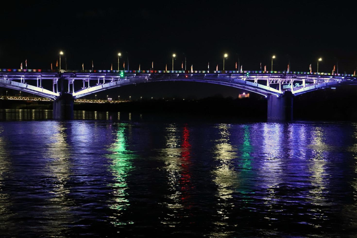 de lichten van de brug zijn weerspiegeld in de nacht rivier. ongericht. foto