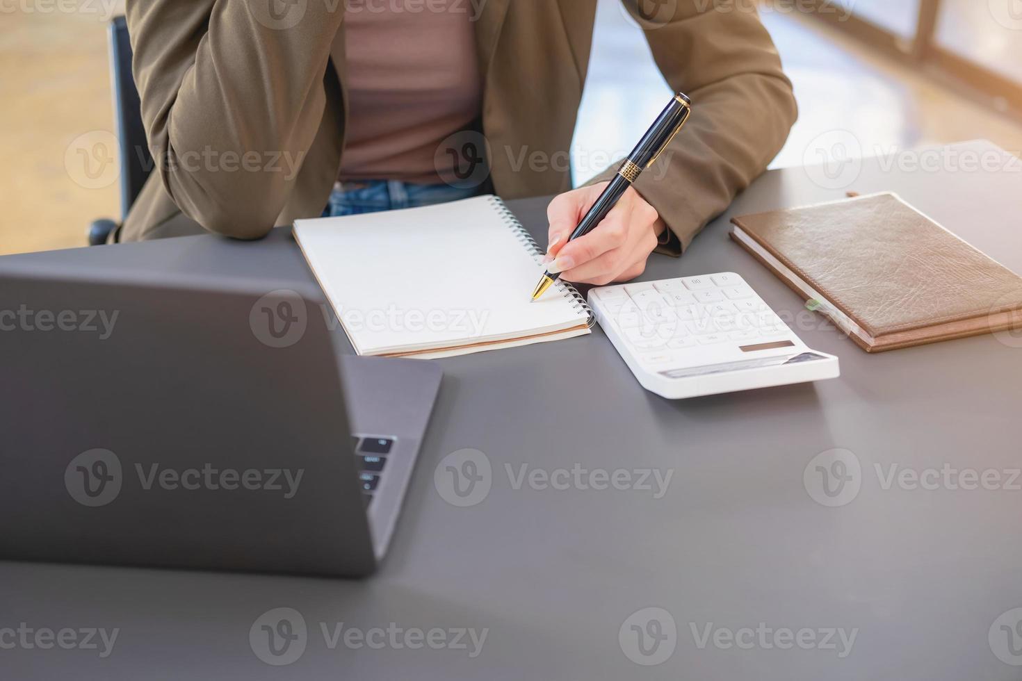 marketing, financiën, boekhouding, planning, zakenvrouw van bi nationaliteit is pratend met een klant vertegenwoordigen een bedrijf distributeur gebruik makend van een smartphone met laptop pen en kladblok Aan kantoor bureau. foto