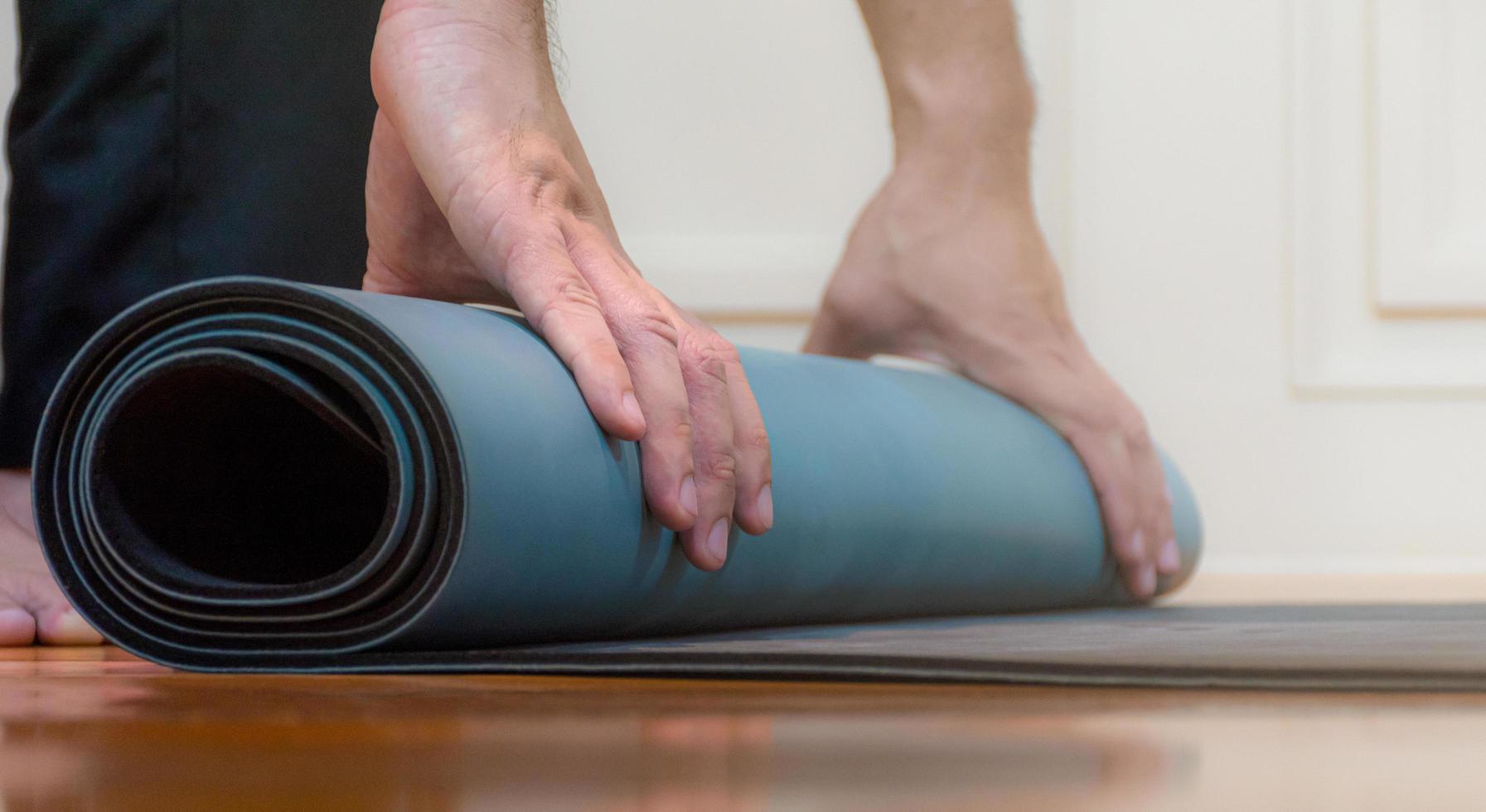 de Mens is gebruik makend van zijn handen naar rollen groen yoga foto