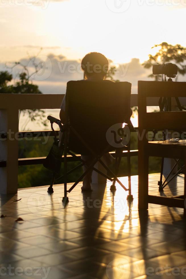 silhouet Dames persoon kom tot rust alleen Aan een stoel en genieten tropisch natuur in de ochtend- met koffie tijd, vakantie vakantie, leven vrijheid concept. foto