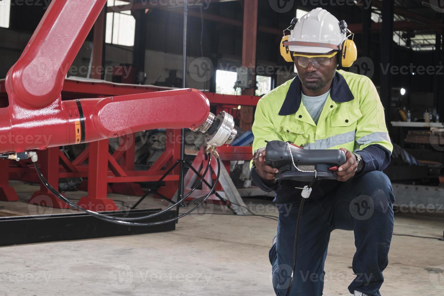 een Afrikaanse Amerikaans productie ingenieur test en controle robot arm in mechanisch fabricage fabriek, intelligent automatisch machines in industrieel bedrijf, en futuristische technologie innovatie. foto