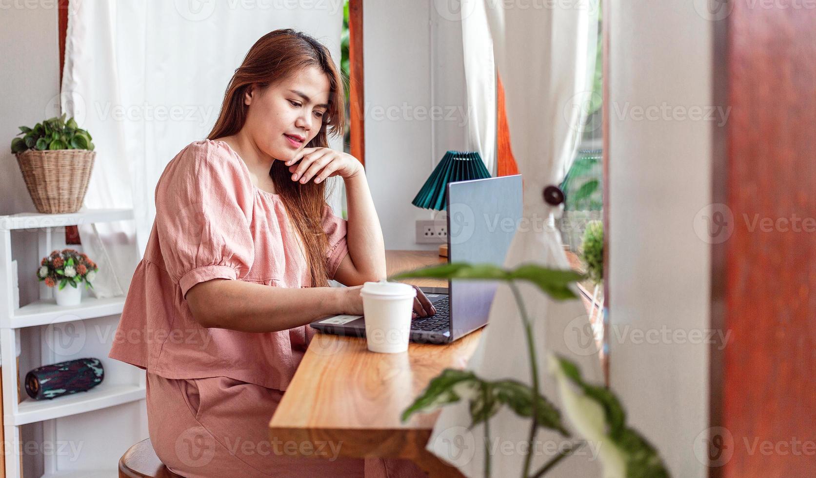 een gelukkig vrouw Bij een cafe gebruik makend van een laptop. jong wit vrouw zittend in een koffie winkel bezig werken Aan haar laptop. foto