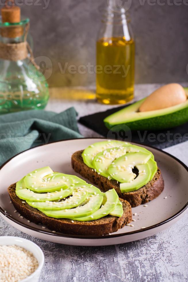 boterhammen Aan rogge brood met avocado en sesam zaden Aan een bord. gezond voedsel. verticaal visie foto