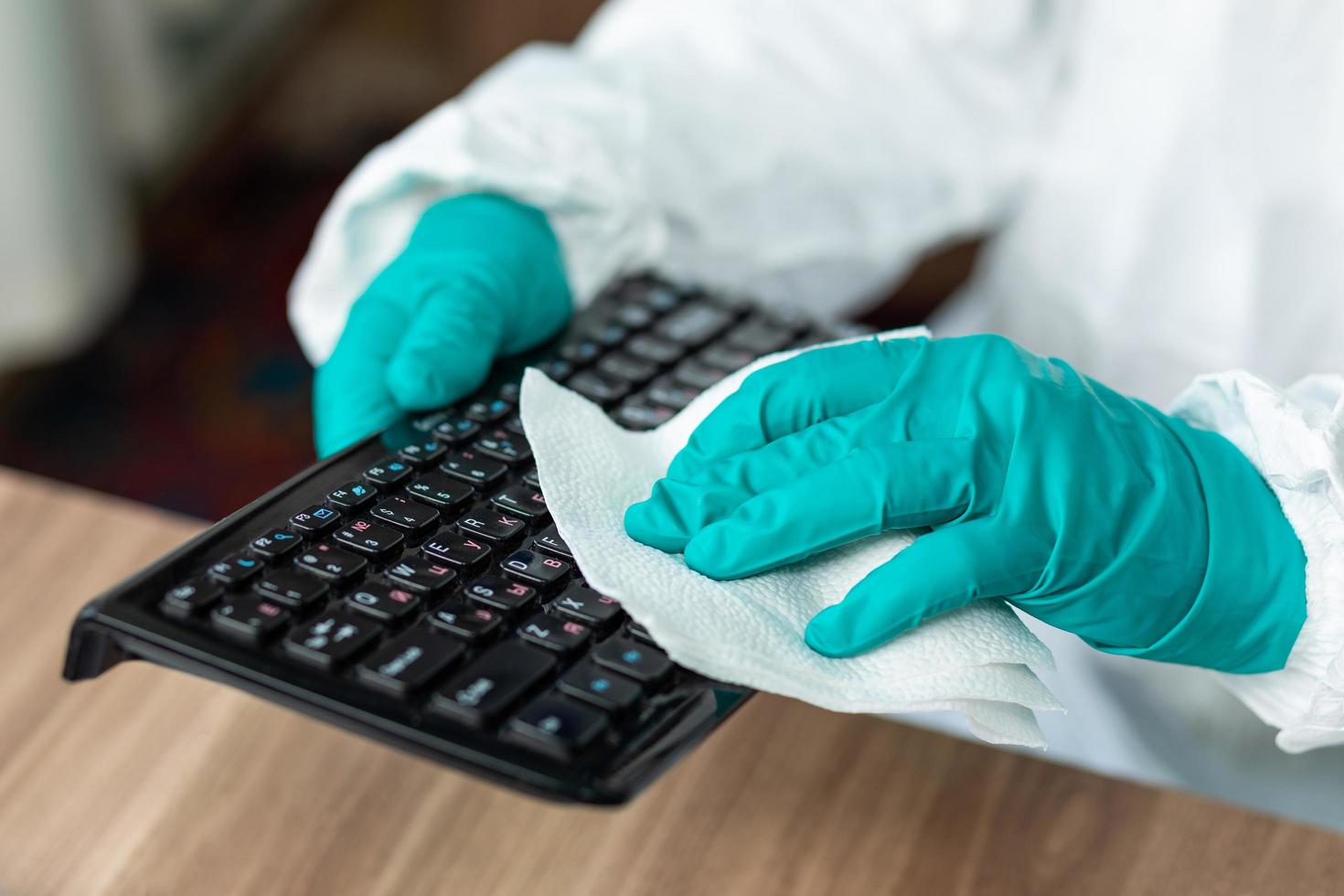 persoon met beschermende uitrusting die een computertoetsenbord schoonmaakt foto