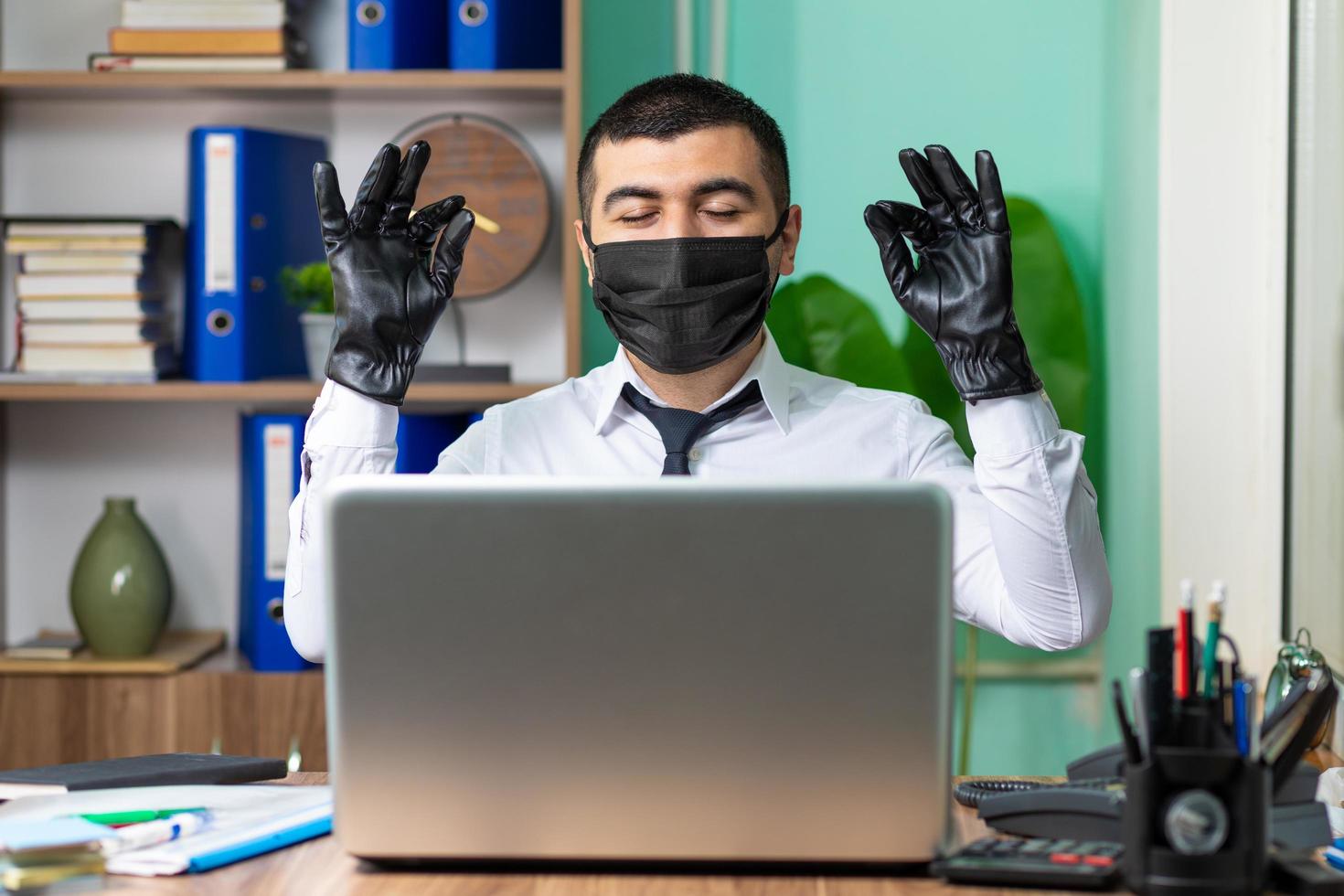 jonge zakenman die op laptop met zwarte medische beschermend masker en handschoenen werkt foto