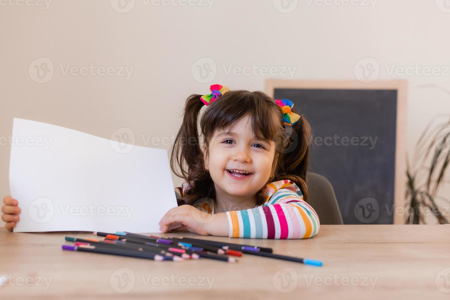 een schattig weinig meisje in een tekening les houdt een leeg wit vel in haar handen, een ruimte voor tekst. kinderen en creativiteit. hoog kwaliteit foto