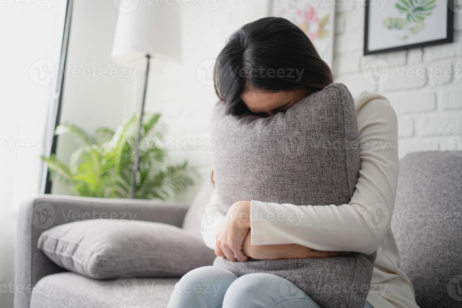 ongelukkig vrouw eenzaam Bij huis. ze was zittend Aan de sofa en schuilplaats haar gezicht Aan de kussen. depressie concept. foto