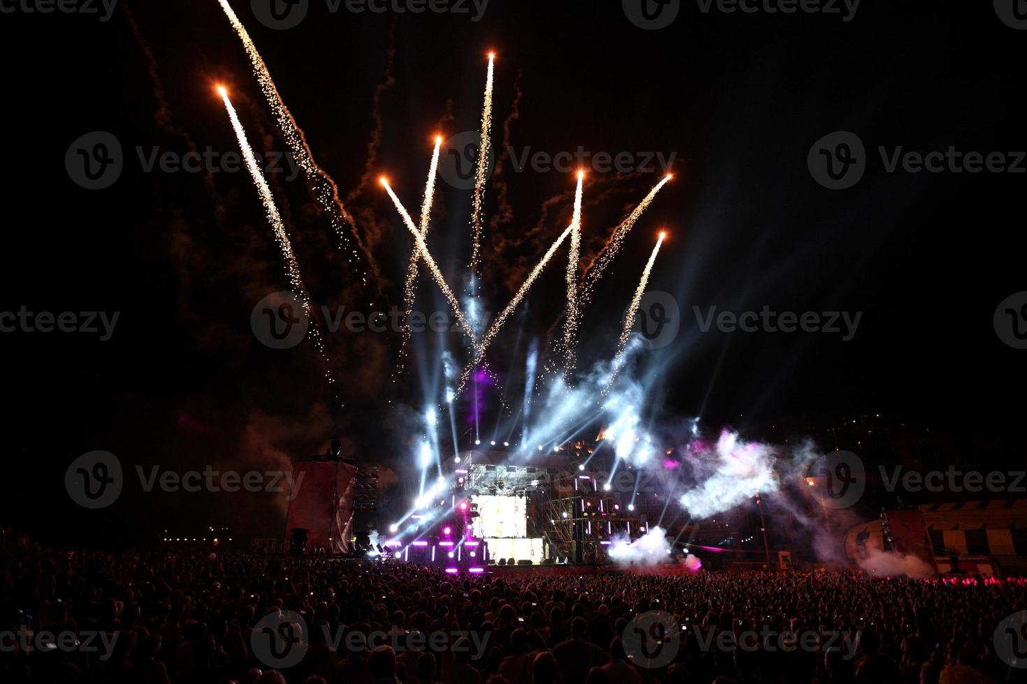 groet en vuurwerk Aan een muziek- stadium met schijnwerpers Bij nacht. foto