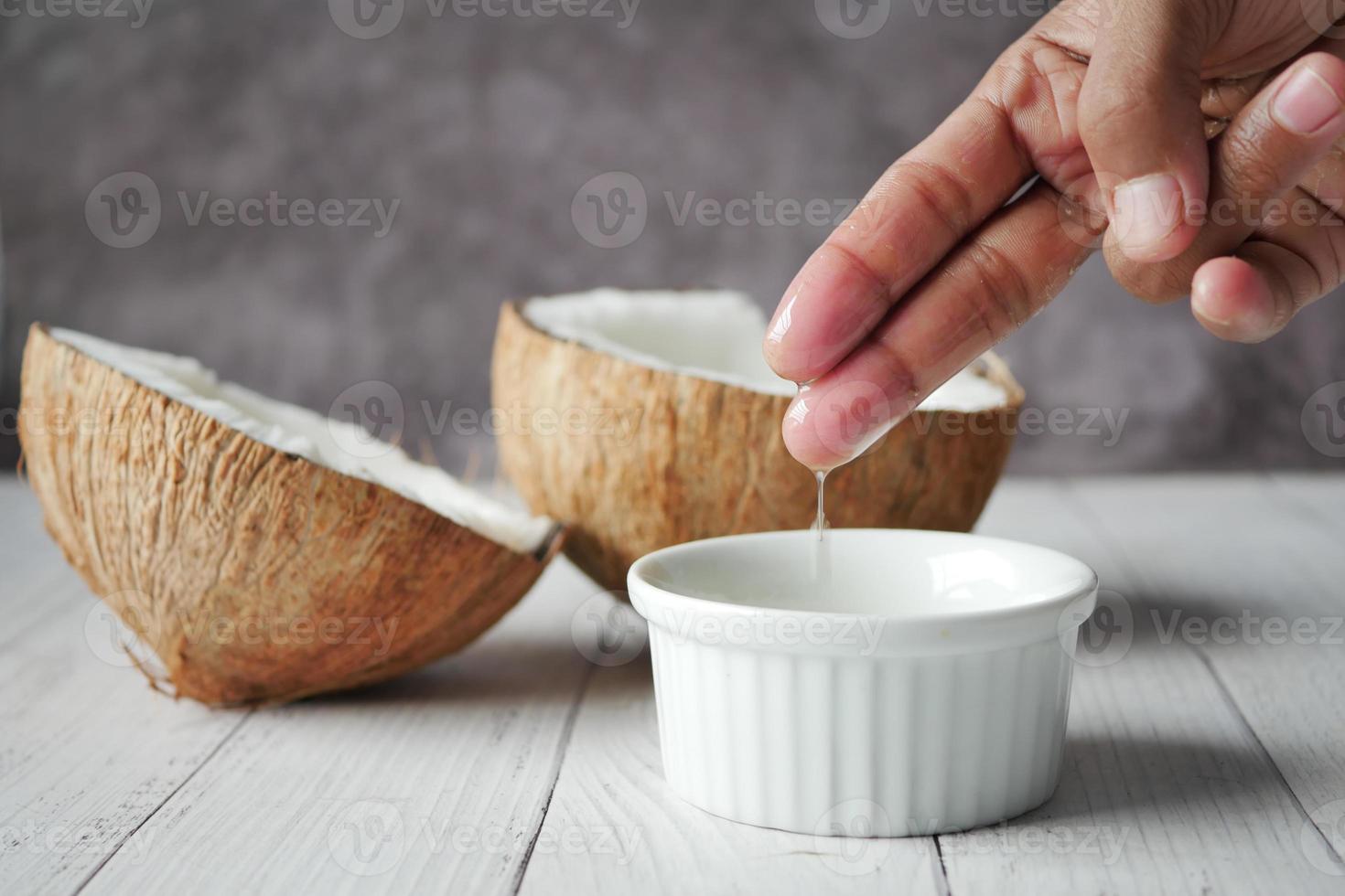 plakje verse kokosnoot en fles olie op tafel foto