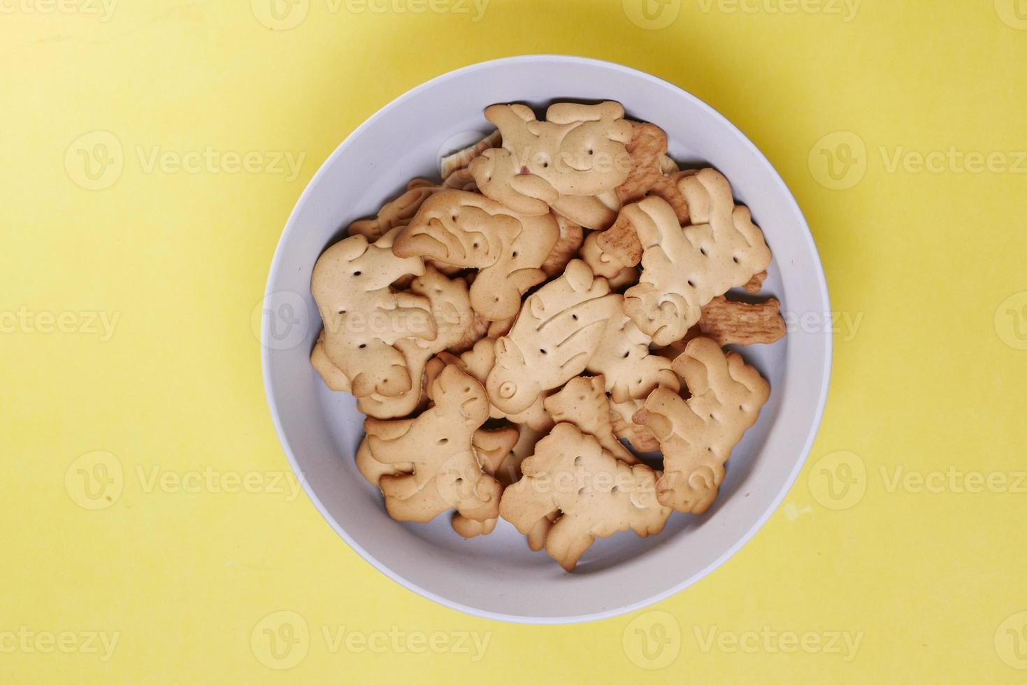 dier vorm zoet koekjes in een wit kom geel achtergrond foto