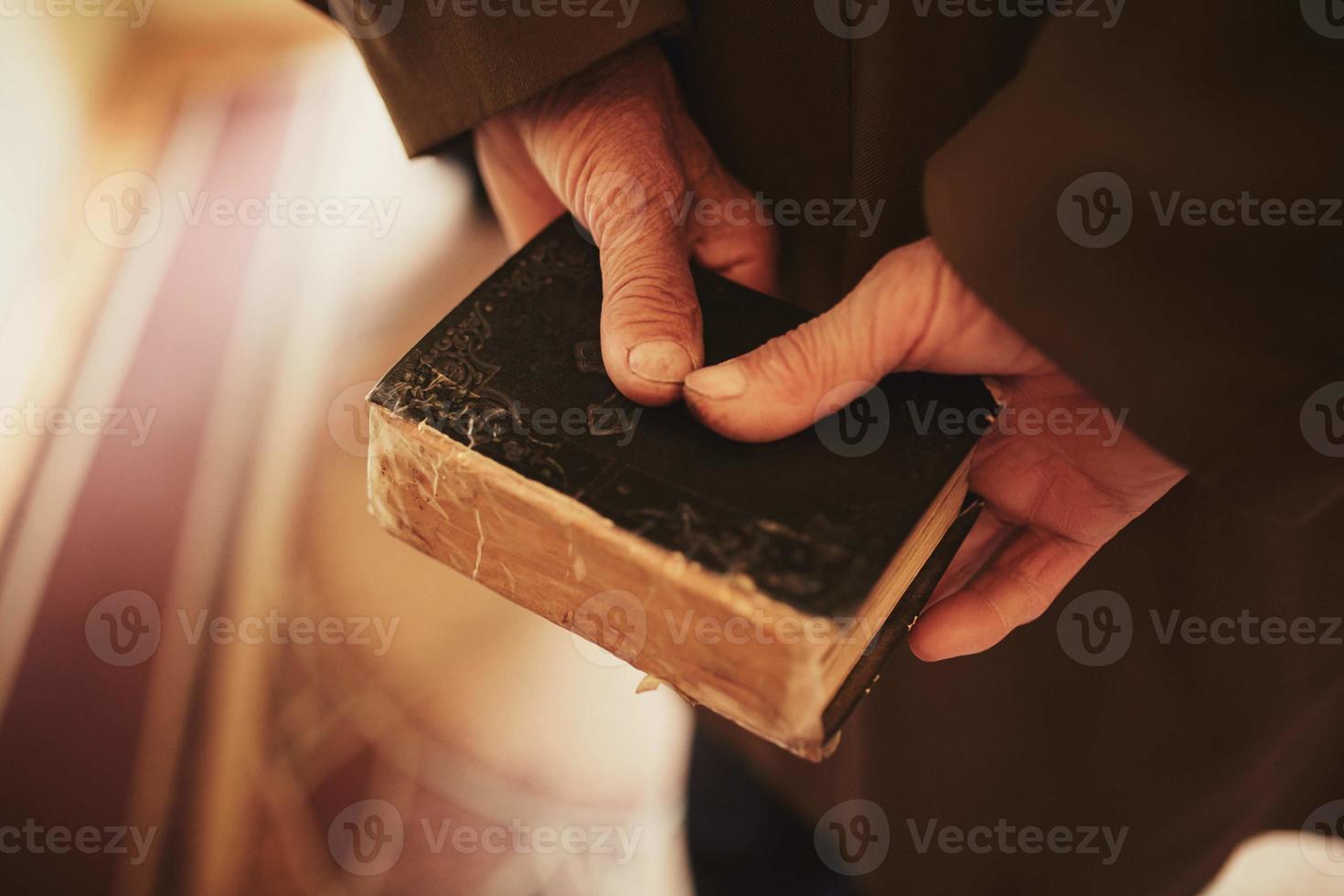 een boek in de handen van een oud Mens. weinig Bijbel foto