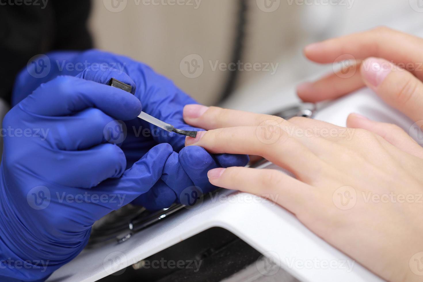 close-up shot van manicure in een schoonheidssalon. meester tijdens een manicure. meester manicure lakt de gel op de nagels van een vrouwelijke cliënt. het concept van schoonheid en gezondheid. foto