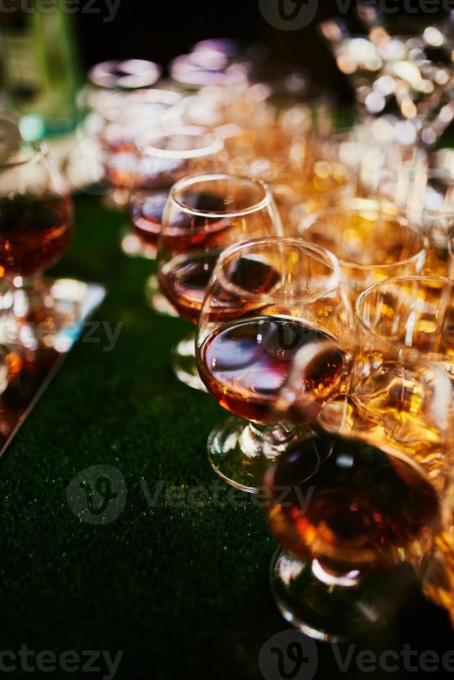 bril met cognac, whisky staan Aan de bar. een veel van bril met cognac. alcohol in de bril. divers alcohol drankjes staand Aan bar. bril met cognac Aan de bar foto