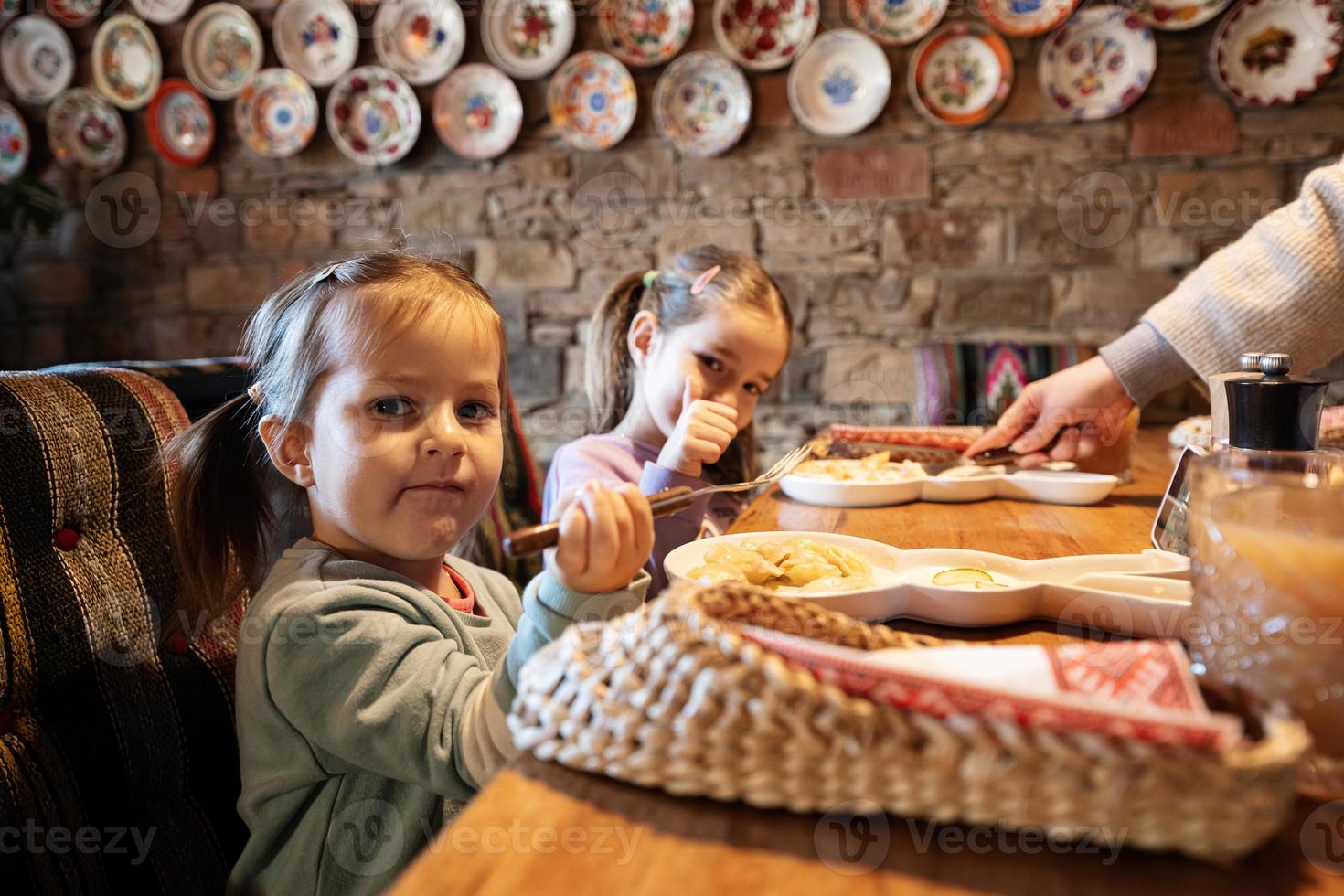 familie hebben een maaltijd samen in authentiek oekraïens restaurant. meisjes kinderen eten knoedels. foto