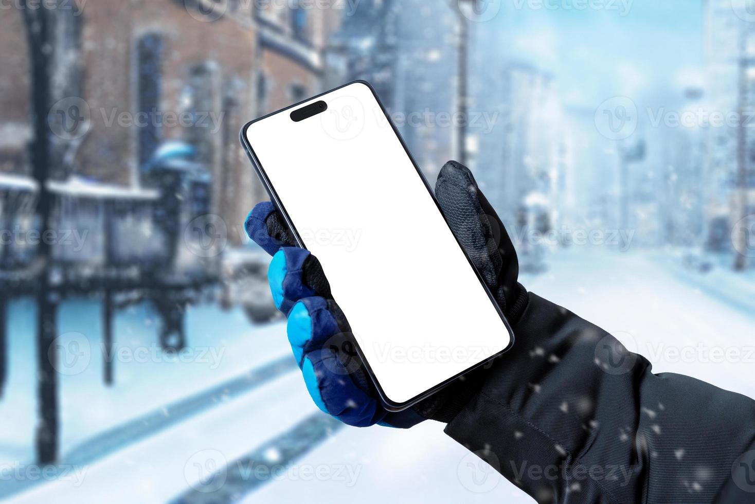 gebruik makend van een mobiel telefoon Aan de straat terwijl het is sneeuwen. geïsoleerd Scherm voor app Promotie. man's hand- Holding een telefoon met een winter handschoen foto
