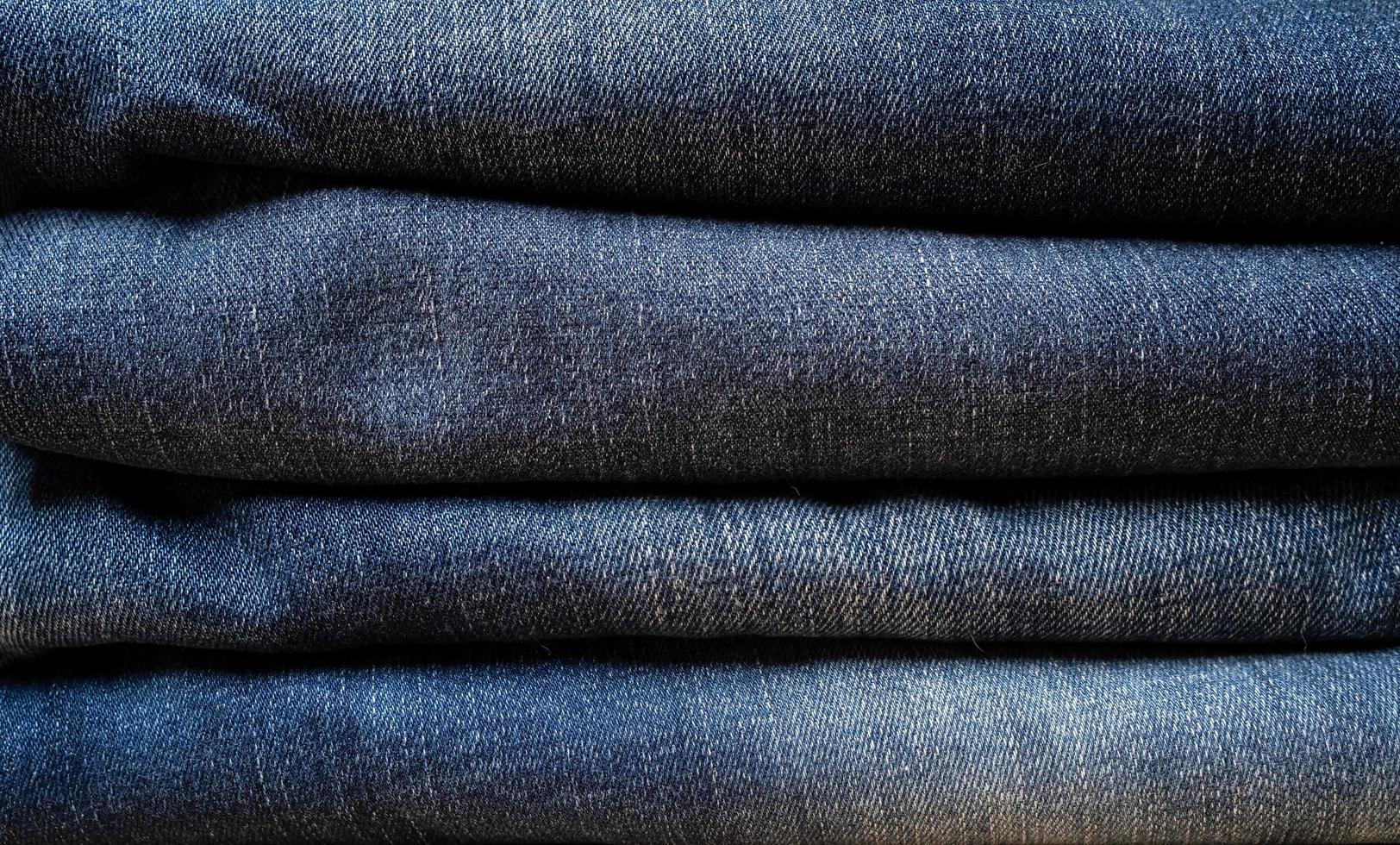 jeans gevouwen in een stapel. getextureerde achtergrond. kopiëren ruimte. concept van de handel industrie, verkoop. foto