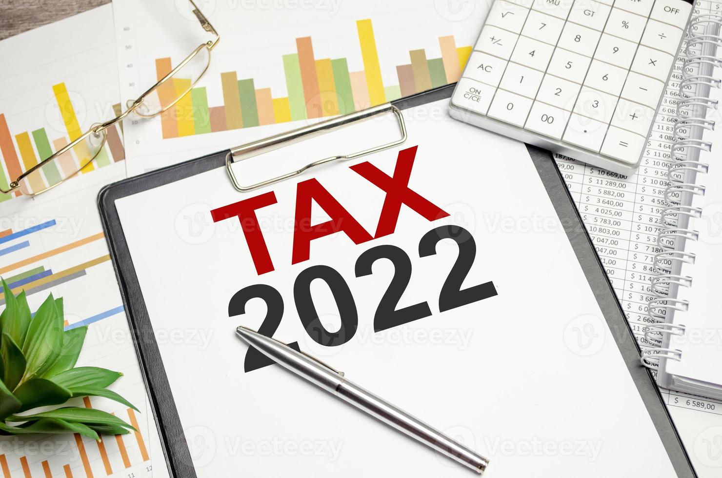 belasting 2022, belastingheffing systeem. woord Aan wit notitieboekje en grafieken met bril en rekenmachine foto