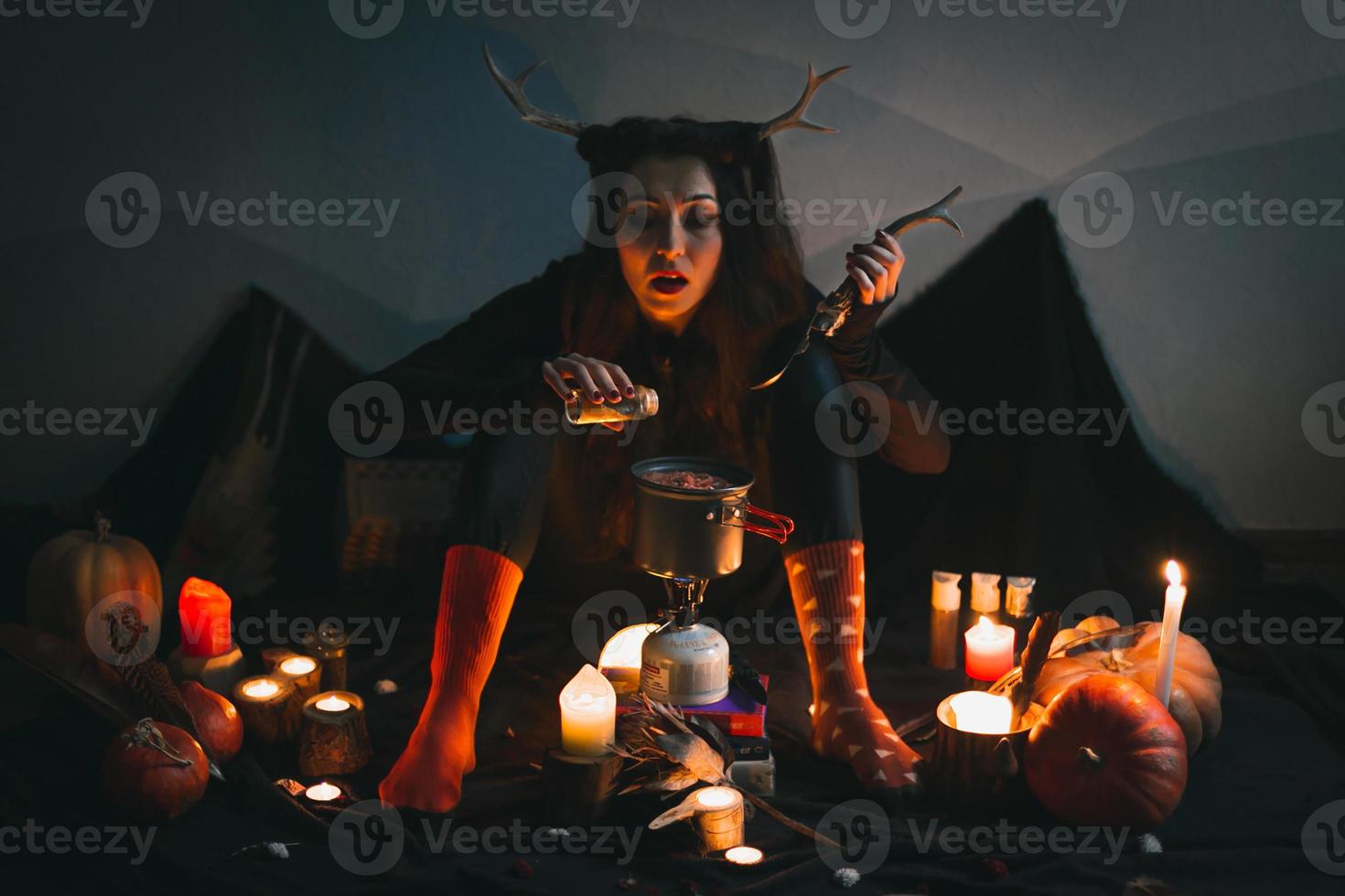 dichtbij omhoog vrouw sjamaan met hoorns sprenkeling kruiderij in soep portret afbeelding foto