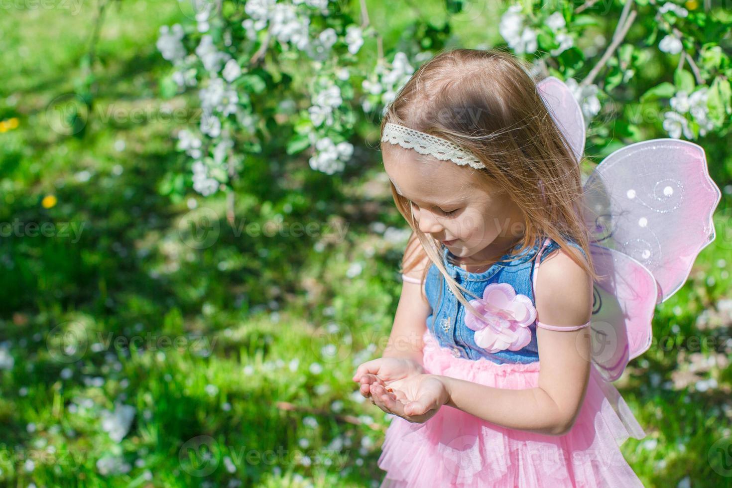 weinig meisje met een lieveheersbeestje in de handen Bij bloeiend appel boomgaard foto