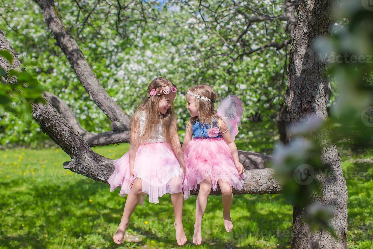 weinig aanbiddelijk meisjes met vlinder Vleugels Aan bloeiende appel boom foto