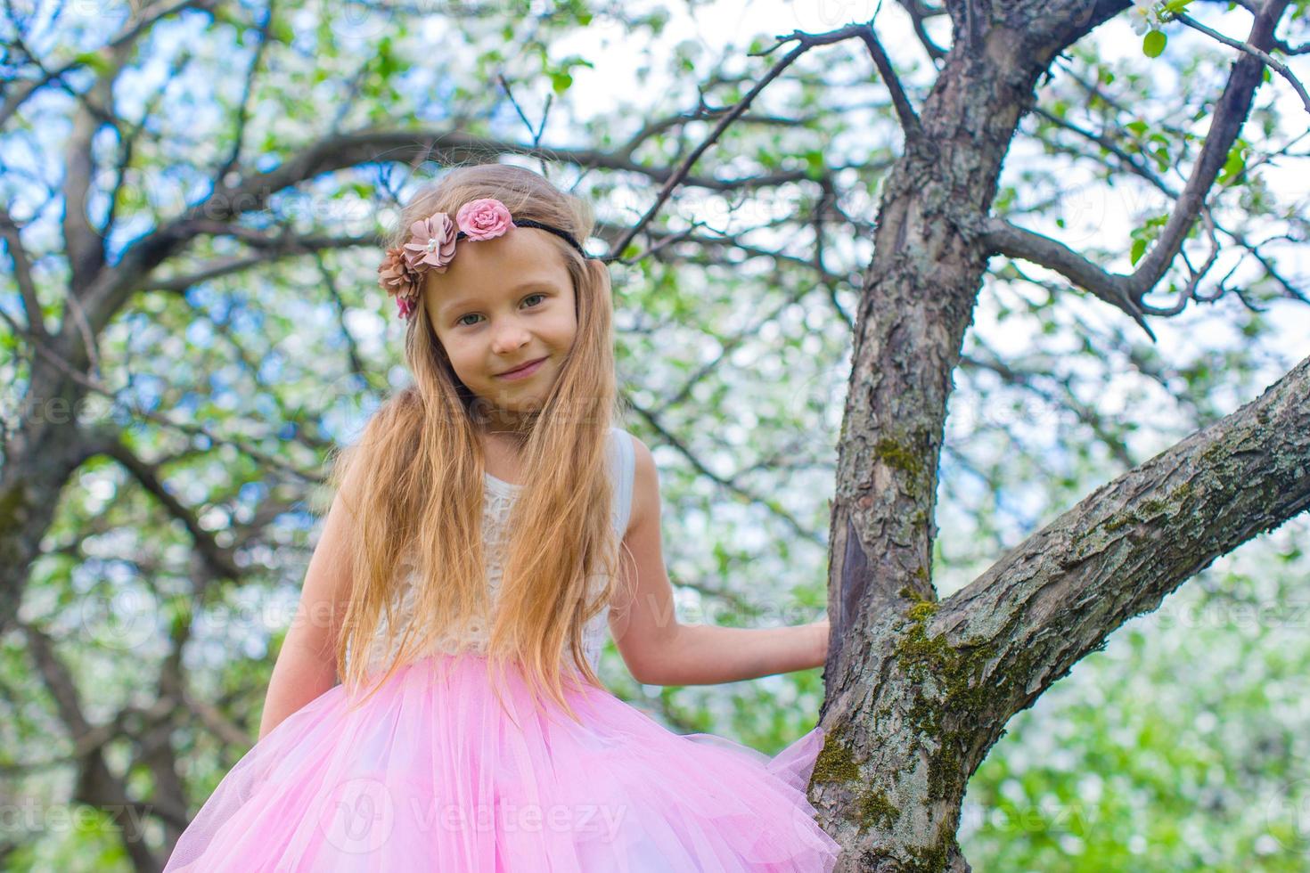 portret van weinig schattig meisje in bloeiende appel tuin foto