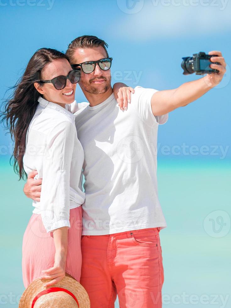 gelukkig paar nemen een selfie foto Aan wit strand. twee volwassenen genieten van hun vakantie Aan tropisch exotisch strand