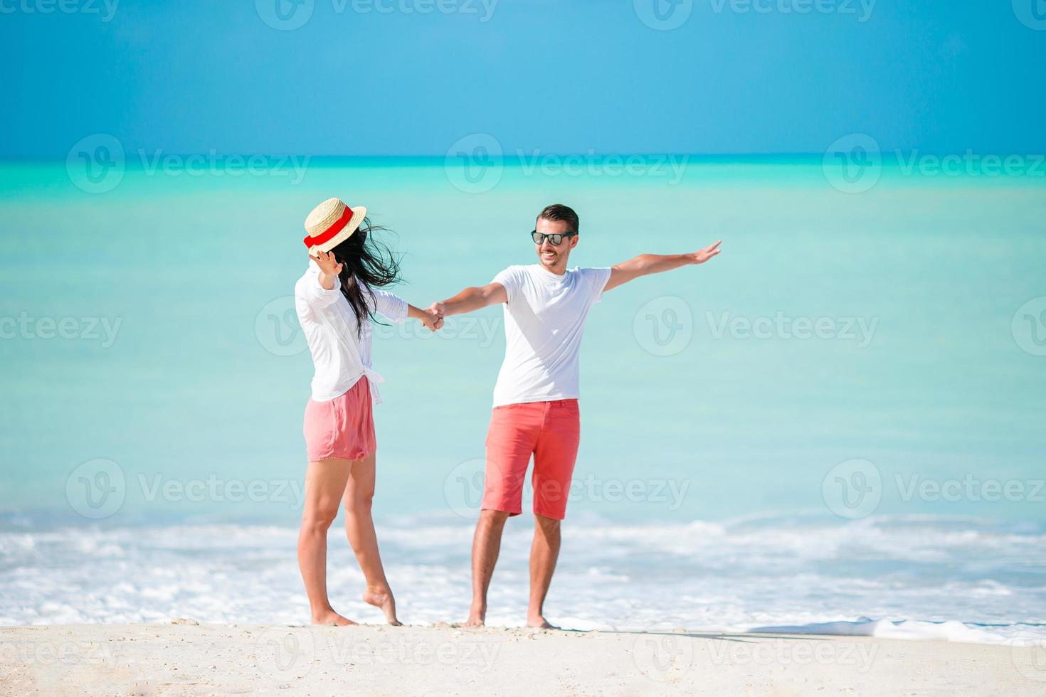 jong paar wandelen Aan tropisch strand met wit zand en turkoois oceaan water foto