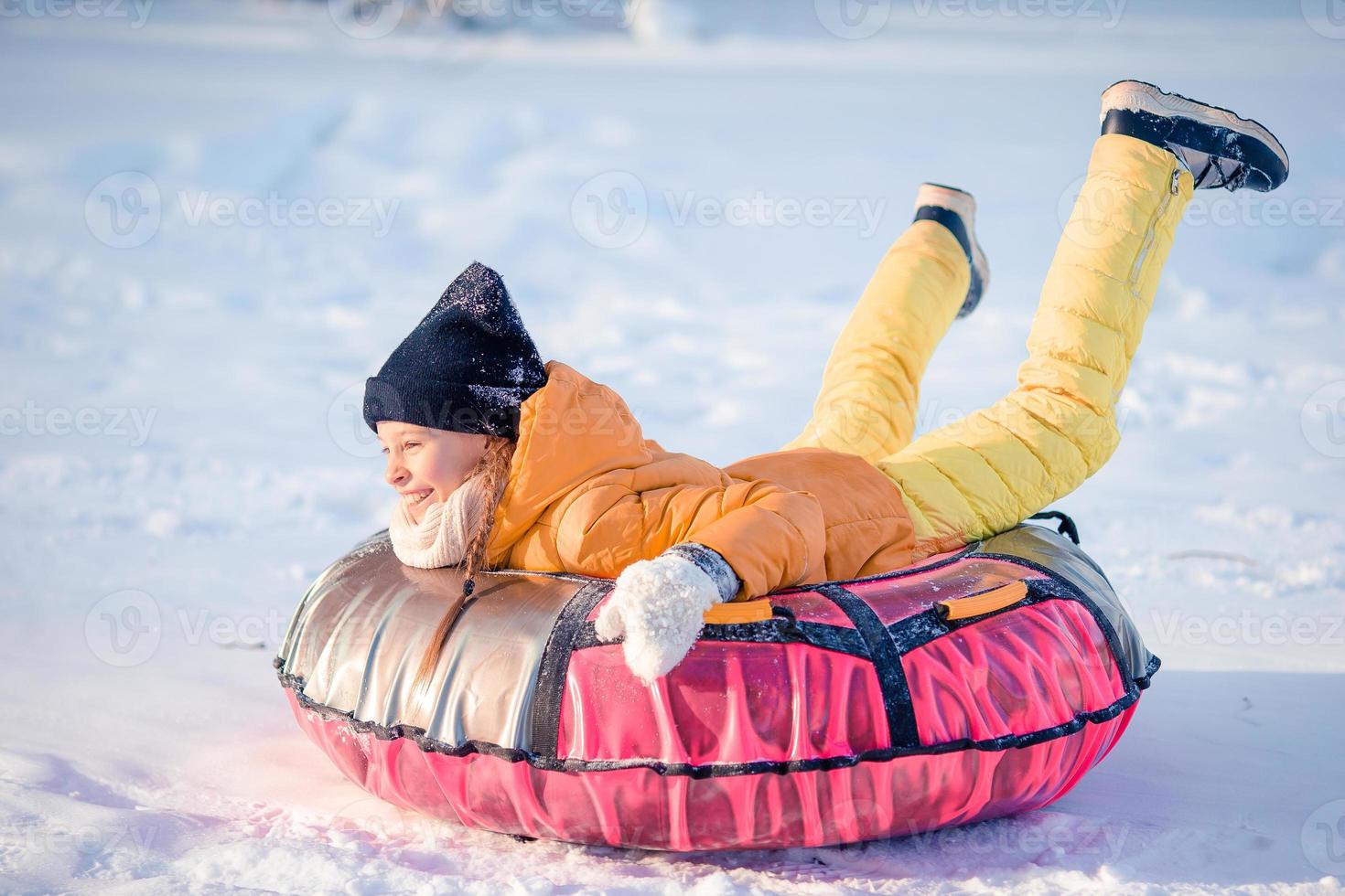 aanbiddelijk weinig gelukkig meisje rodelen in winter besneeuwd dag. foto