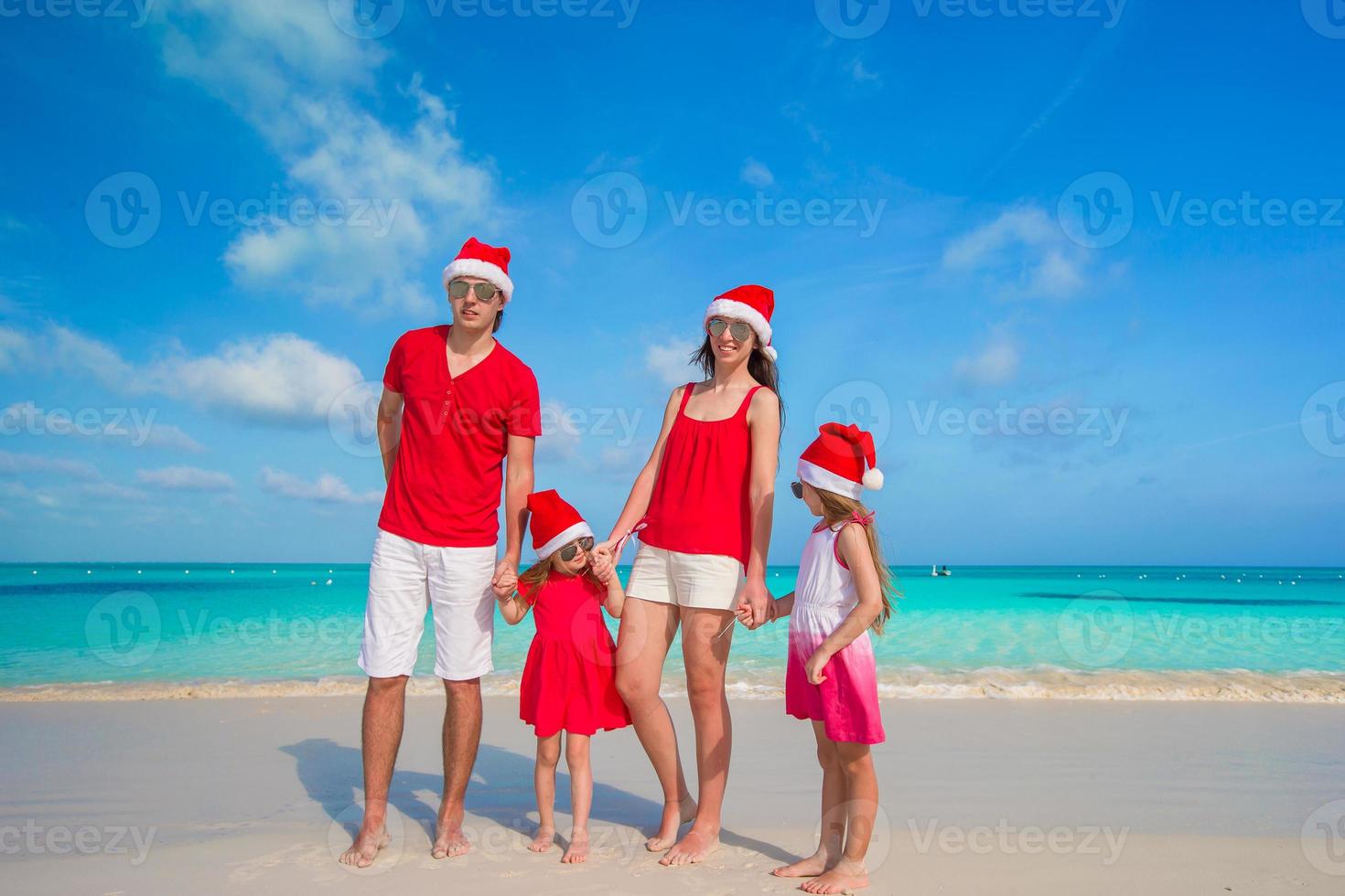 gelukkig familie met twee kinderen in de kerstman hoed Aan zomer vakantie foto