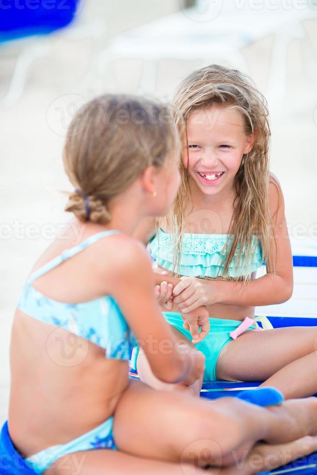twee weinig gelukkig meisjes hebben een veel van pret Bij tropisch strand spelen samen foto