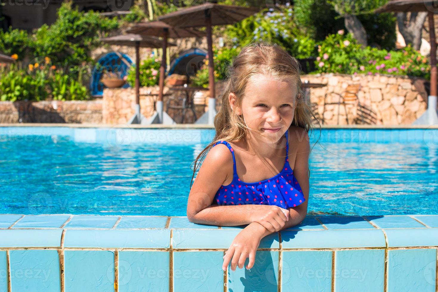 schattig gelukkig weinig meisje in de zwemmen zwembad op zoek Bij camera foto