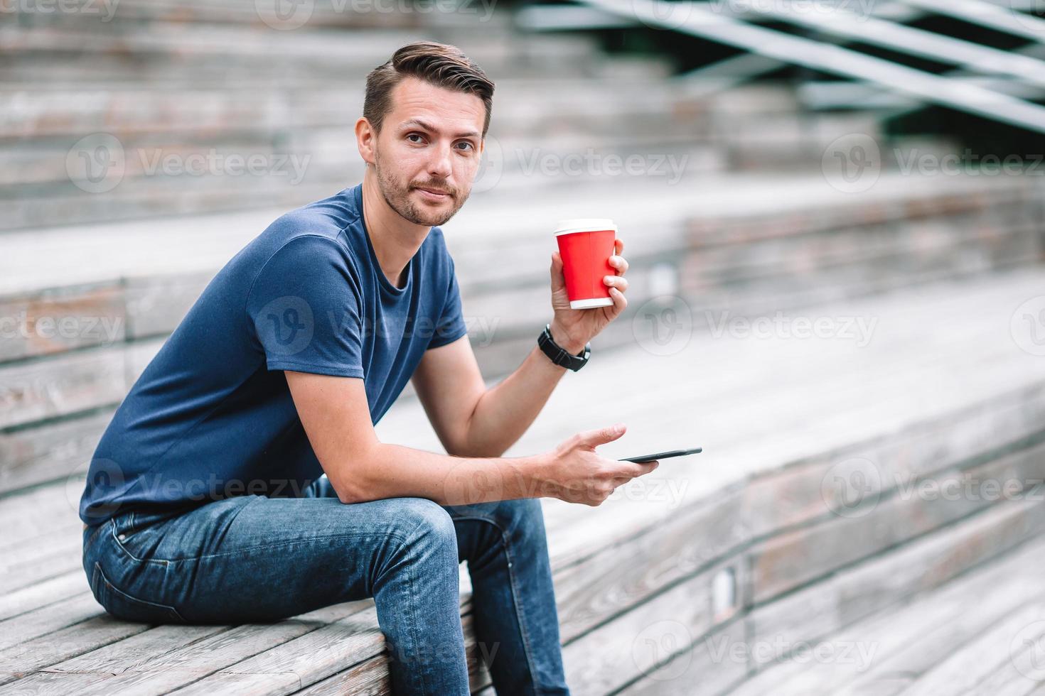 Mens is lezing tekst bericht Aan mobiel telefoon terwijl wandelen in de park foto