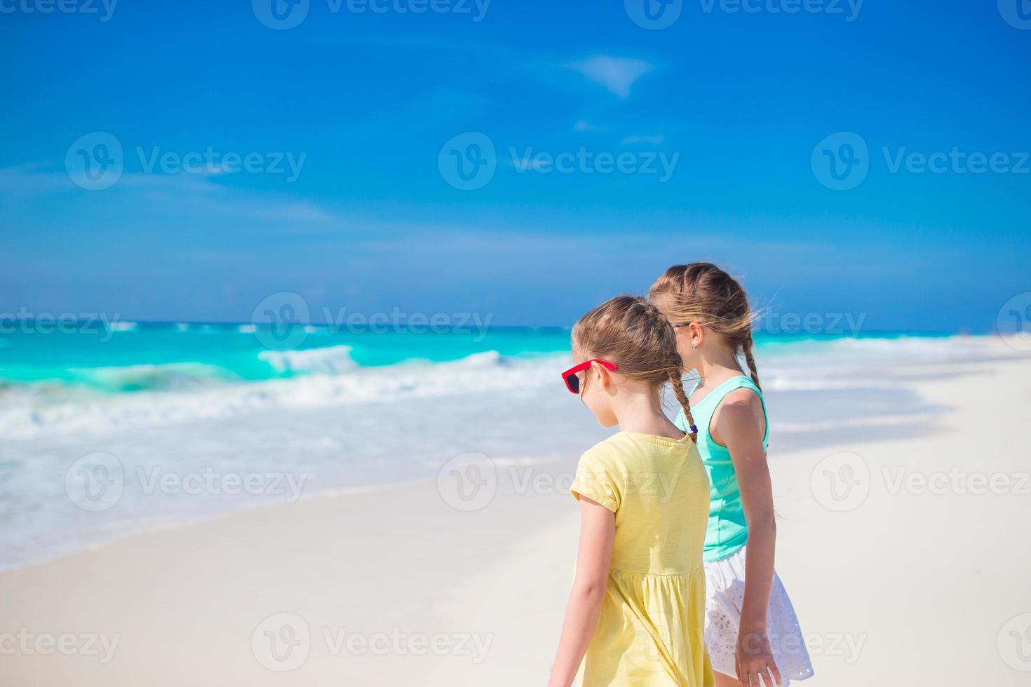weinig meisjes hebben pret Bij tropisch strand spelen samen Aan de kust foto