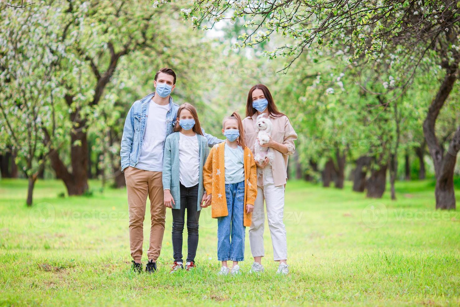 aanbiddelijk familie in bloeiend kers tuin in maskers foto