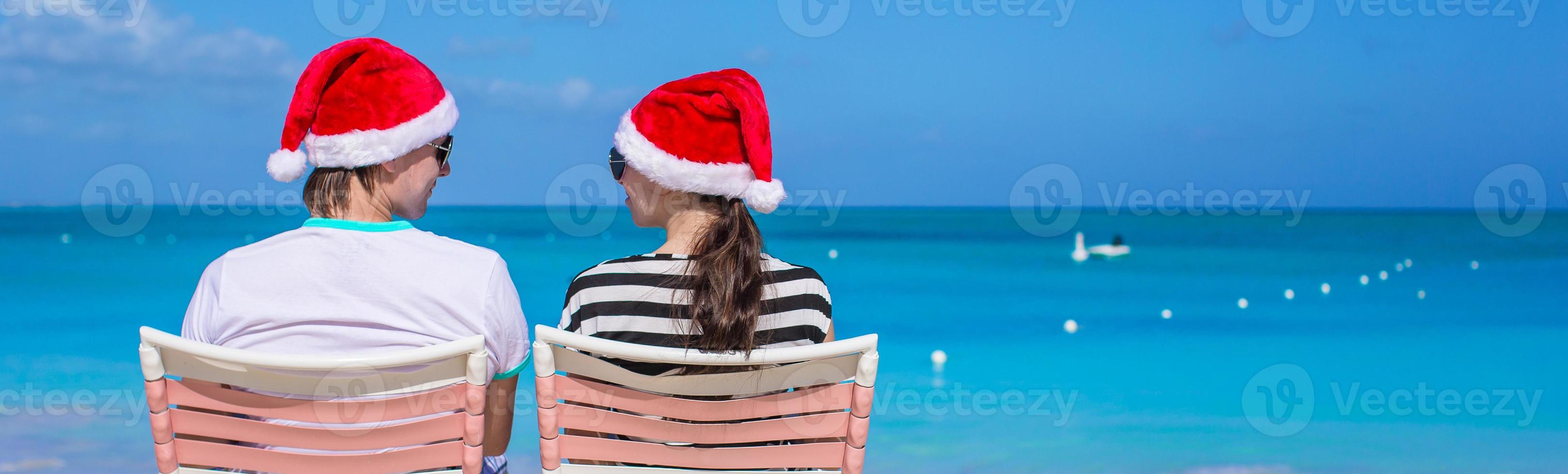 jong romantisch paar in de kerstman hoeden gedurende strand vakantie foto