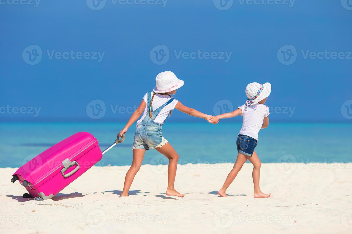 weinig toeristen meisjes met groot koffer Aan tropisch wit strand foto