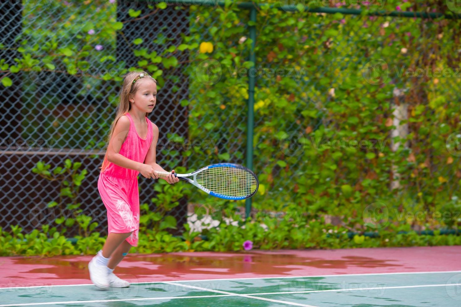 klein meisje dat tennis speelt op de baan foto