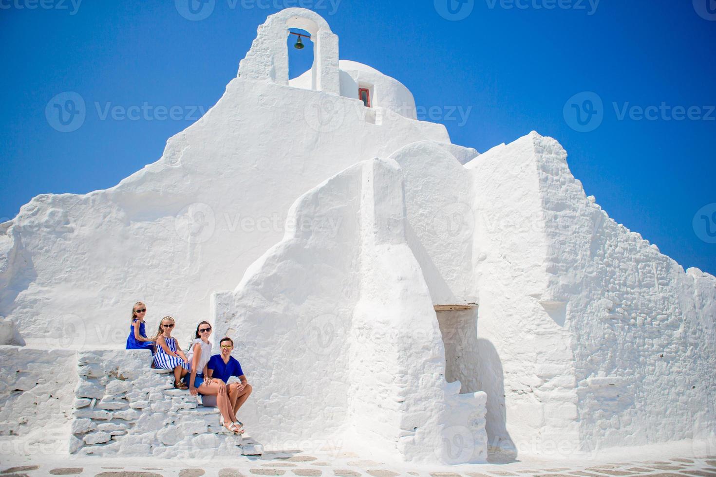 familie van vier Aan de trap van paraportiani kerk Aan Mykonos eiland, in Griekenland foto