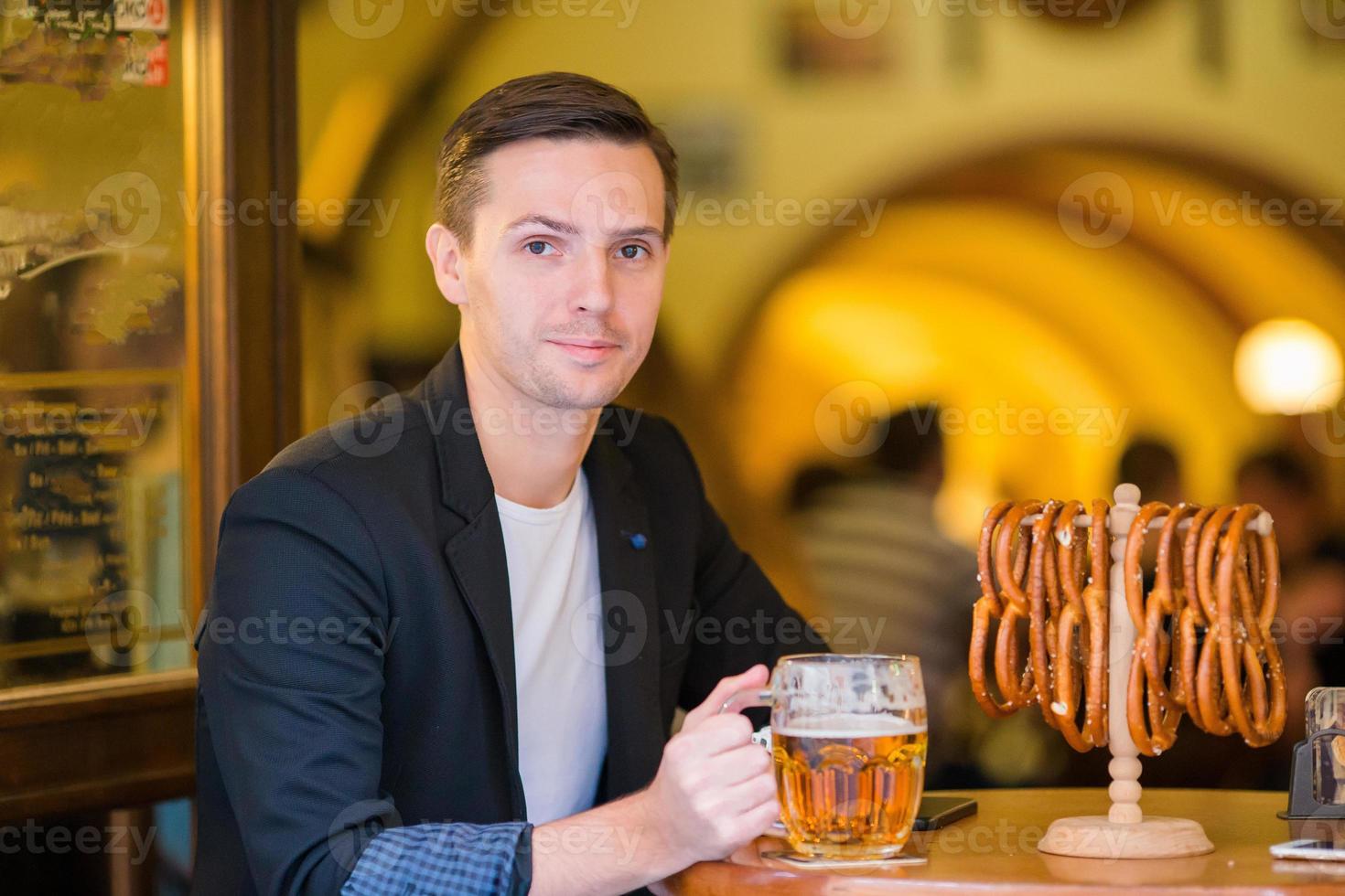 jong Mens met pint van bier en gezouten zacht pretzels in bier sport bar foto