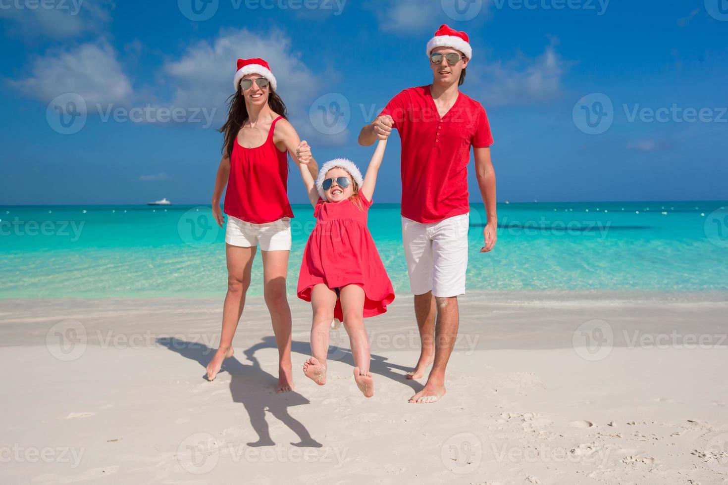 gelukkig familie in Kerstmis hoeden hebben pret Aan wit strand foto