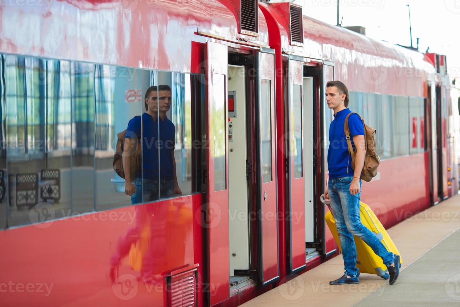 jong Kaukasisch Mens met bagage Bij station op reis door trein foto