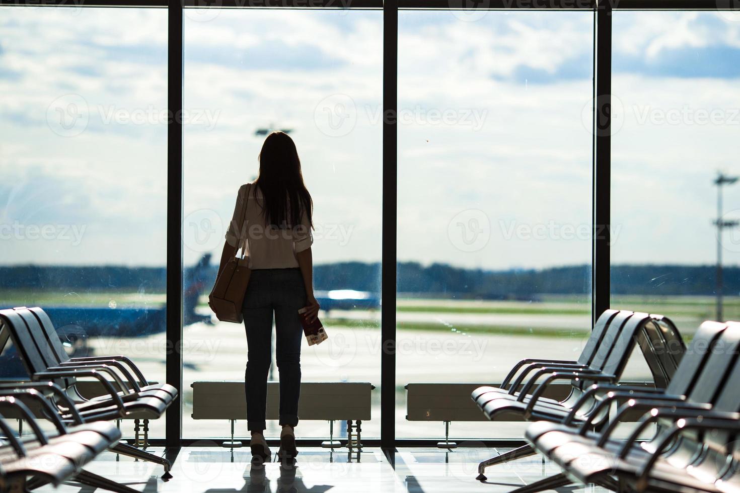 silhouet van vrouw in een luchthaven lounge aan het wachten voor vlucht vliegtuig foto