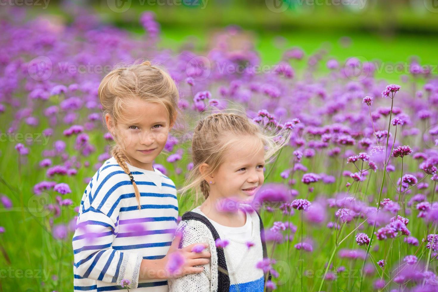 weinig aanbiddelijk meisjes wandelen buitenshuis met bloemen foto