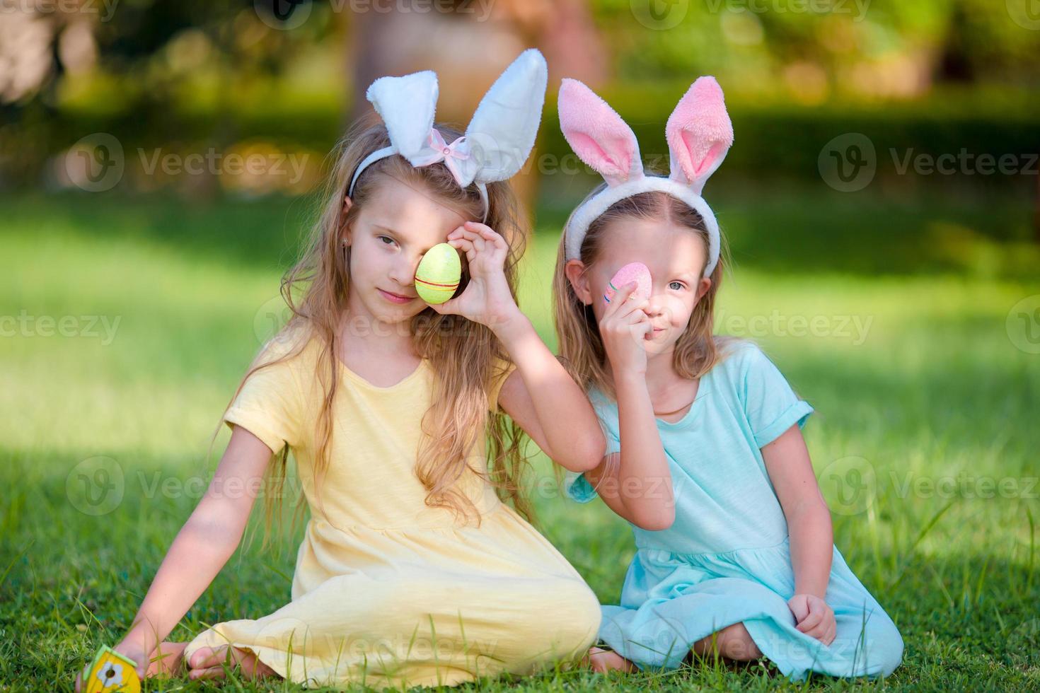 twee schattige zusjes die konijnenoren dragen op paasdag buitenshuis foto